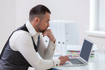 male business professional typing on a laptop